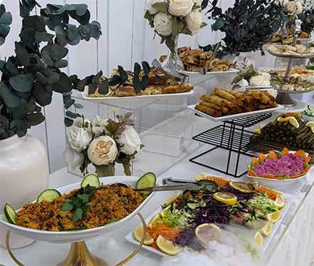 Buffet-Ansicht mit Warmhaltebehältern (Chafing Dishes), die türkischen Reis (Pilav), Fleischgerichte und Beilagen wie Pommes und Nuggets für Kinder enthalten.